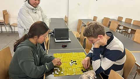 Drei Personen spielen das Go Spiel